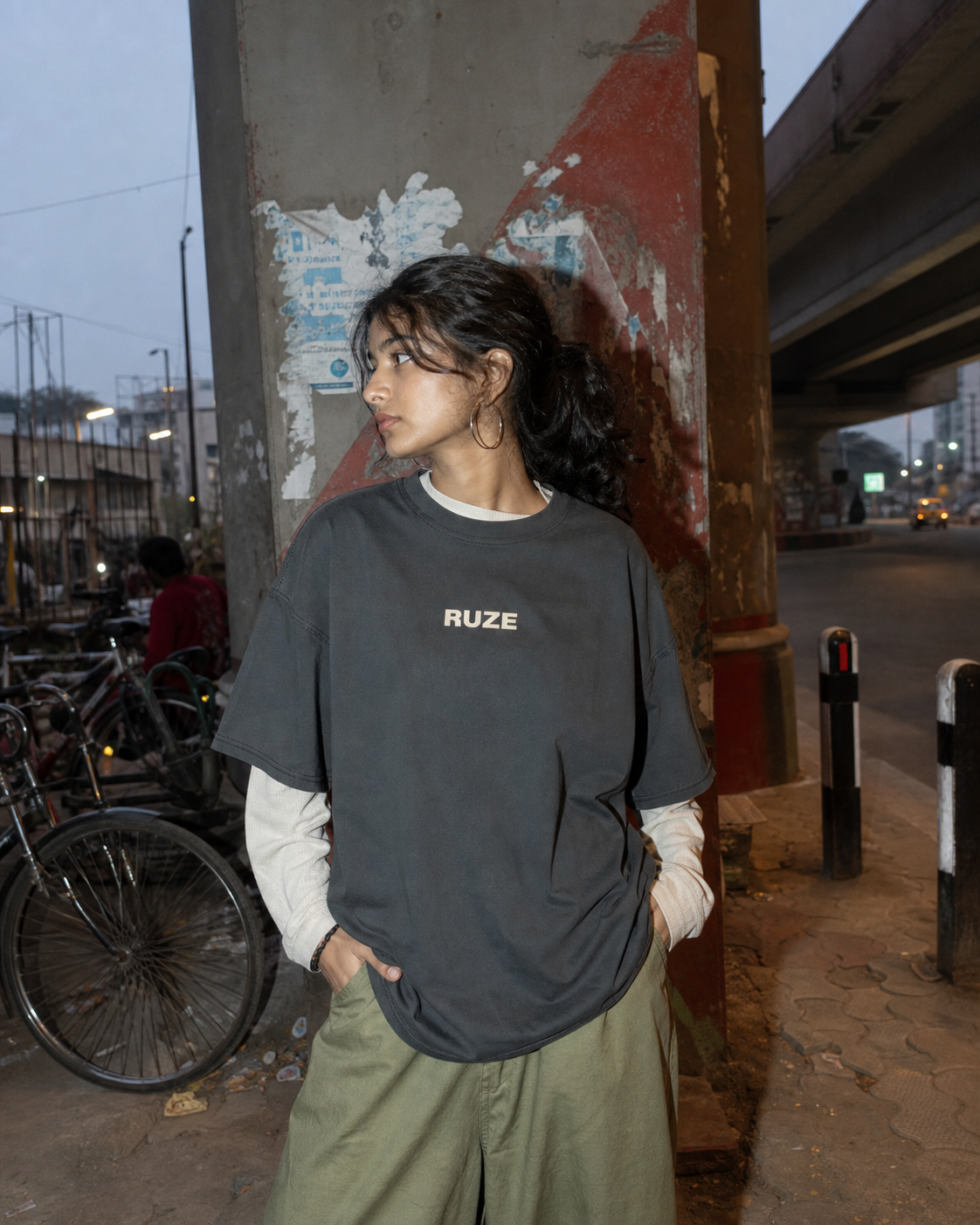RUZE promotional tee under a concrete flyover at dusk